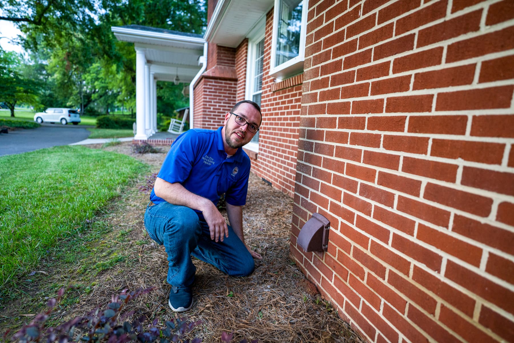 Drew Cline inspecting the foundation and grade outside a brick home